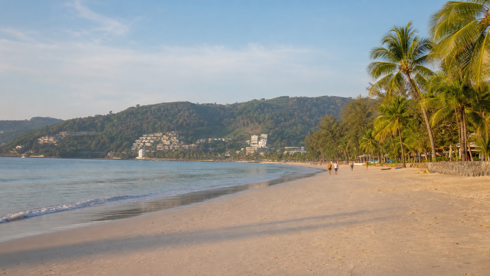 Quieter north Patong Beach in the morning with soft sand, calm water, palms, and fewer people