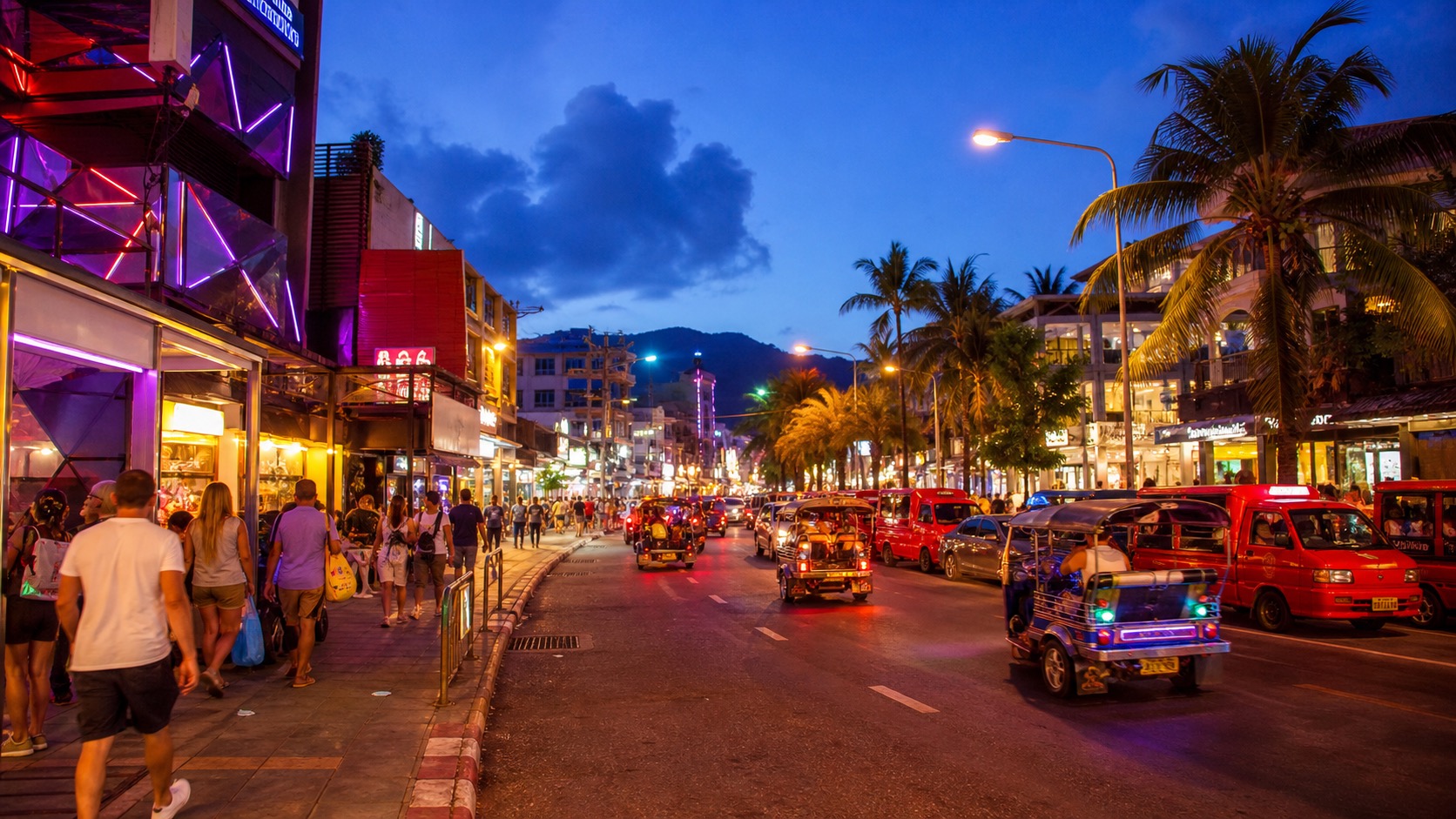 Patong Beach Road at blue hour with neon lights, tuk-tuks, shops, and evening nightlife energy