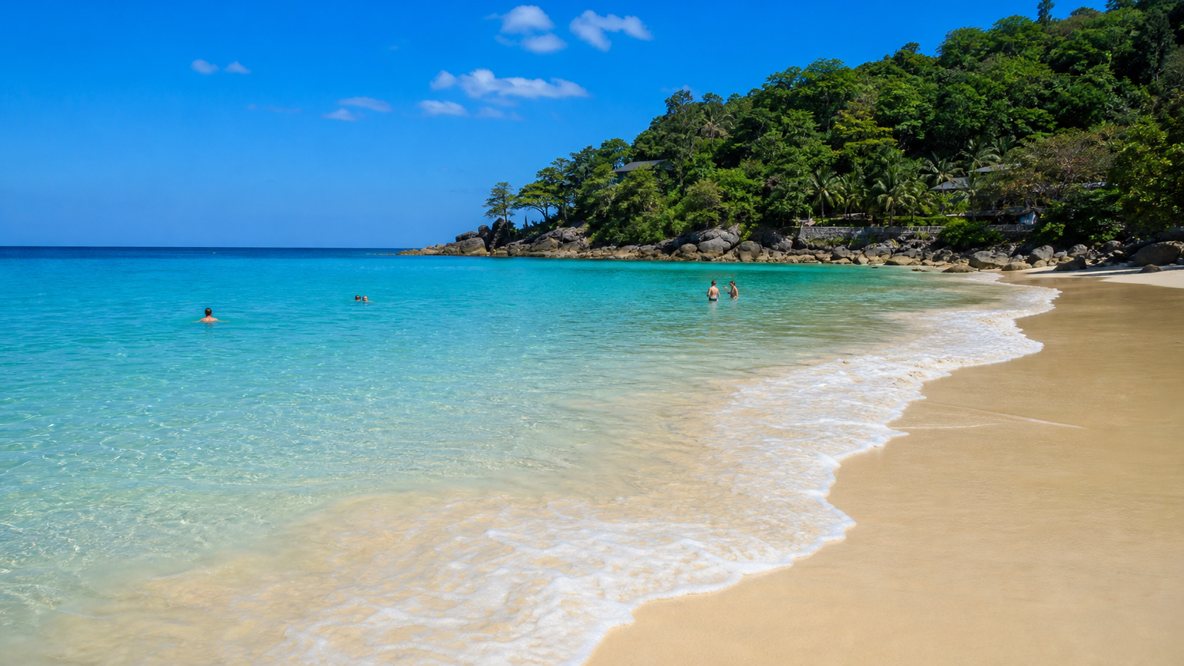 Calm clear turquoise water and swimmers at Surin Beach Phuket in high season
